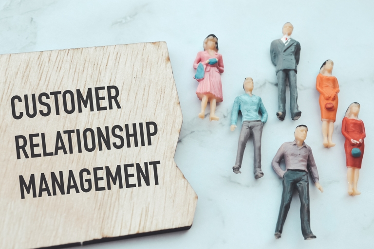 Customer relationship management font over a piece of wood next two 6 people figurines