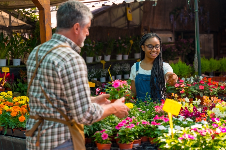 Young female customer buying flowers from a gardener.